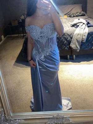 Ljusblå långklänning med spetsdetaljer - Elegant ljusblå långklänning med offshoulder och vacker spets upptill. Klänningen har en figurnära passform, transparenta partier i midjan och draperad kjol med slits. Perfekt för bal eller student. Materialet är väldigt skönt, speciellt för en varm baldag! Klänningen är köpt för 1500kr! BARA ANVÄND EN GÅNG. Skulle säga att färgen är en väldigt ljus nyans av lila blandat av blått!