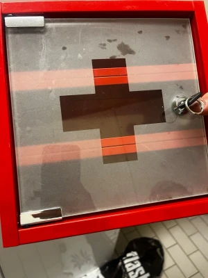 Röd medicinskåp med glasdörr - Säljer ett rött medicinskåp i metall med glasdörr och kors på framsidan. Skåpet har två hyllplan och lås med nyckel. Perfekt för att förvara mediciner eller första hjälpen-prylar hemma.