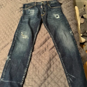 Dsquared2 blå distressed jeans - Blå jeans från Dsquared2 med slitna detaljer och  slitningar framtill. Jeansen har en rak passform. Nypris runt 2400kr, barnstorlek 16Y men är som typ midja 30/31 och längd 31/32 på ett ungefär
