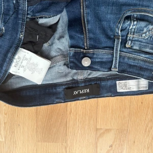 Blå Replay hyperflex Anbass jeans herr, waist 28, length 32  - Snygga blå Replay Anbass jeans med klassisk femficksdesign och diskreta slitningar. Jeansen har raka ben, normal passform och är tillverkade i stretchig bomullsdenim för skön känsla. Märkespatch bak i midjan och stilrena detaljer på bakfickorna.