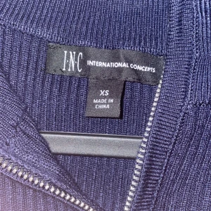 Mörkblå ribbad tröja från INC - Mörkblå ribbstickad tröja från INC International Concepts i storlek XS. Tröjan har lång ärm, halv dragkedja framtill och en klassisk, enkel design som passar perfekt till jeans. Materialet känns mjukt och följsamt. Helt oanvänd 