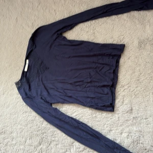 Mörkblå långärmad topp med spets - Mörkblå långärmad topp från Gina Tricot med snygg spetsdetalj över axlar och halsringning. Tunn och mjuk i materialet, perfekt för lager-på-lager eller som den är. Enkel och stilren design med en feminin touch.