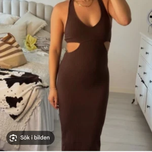 Brun ribbad långklänning med cut-outs - Säljer en brun ribbad långklänning med snygga cut-outs i midjan och halterneck. Klänningen har en tight passform och djup v-ringning, perfekt för dig som vill sticka ut. Materialet är stretchigt och följsamt.