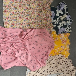 Fem blommiga blusar i olika färger - Fem superfina korta blusar i olika färger och blommiga mönster. En rosa från Bik Bok med små blommor, en svart med lila och vita blommor från Jacqueline de Yong, samt gula, beige och multifärgade med blommigt print. Perfekta för sommarens alla dagar!