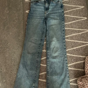 Bootcut jeans Curve S/32 ljusblå - Ljusblå bootcut jeans från Curve i storlek S/32. Klassisk femficksmodell med snygga slitningar och kontrastsömmar. Jeansen har normal passform och är tillverkade i mjukt denimtyg som ger en avslappnad vibe.