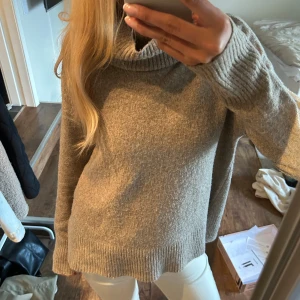 Beige polotröja - Mysig beige polotröja med lös passform och ribbade muddar. Tröjan har en hög, bred polokrage och är stickad som passar perfekt när det är kallt ute. Långärmad och enkel att styla till olika outfits.