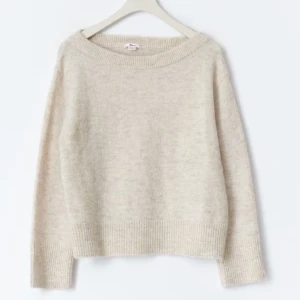 Beige offshoulder stickad tröja - Mysig beige stickad tröja med bred ribbad kant och avslappnad passform. Tröjan har offshoulder-design och långa ärmar, perfekt för lager-på-lager under kyliga dagar. Enkel att styla med jeans eller kjol för en chill look. Nypris 260kr