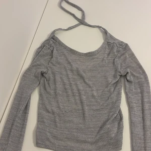 Grå långärmad topp med knyt från Divided - Grå långärmad topp från Divided med ribbad struktur och snygg knyt-detalj Modellen har en rundad halsringning och är tillverkad i ett mjukt, stretchigt material som sitter skönt på kroppen. Perfekt för lager-på-lager eller som den är. 