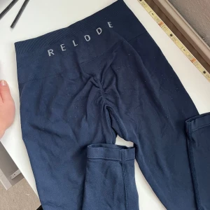 Mörkblå leggings från Relode - Snygga mörkblå leggings från Relode med hög midja och tight passform. Perfekta för träning eller chill, med bred resår i midjan och diskret logga framtill. Mjukt och stretchigt material som sitter skönt hela dagen.