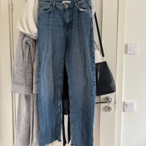 Blå raka jeans med rå kant från NA-KD - Säljer ett par blå jeans från NA-KD med hög midja och raka ben. Jeansen har en snygg rå och fransig kant nertill. säljer dessa då dom inte används. har använt dom max 5 gånger