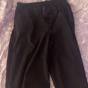 Svarta kostymbyxor i storlek 36 - Stilrena svarta kostymbyxor från Cubus  i storlek 36. Byxorna har klassisk rak passform och är perfekta för en clean och snygg look. De är tillverkade i ett mjukt tyg som känns bekvämt hela dagen. Passar dig som gillar en tidlös och enkel stil.