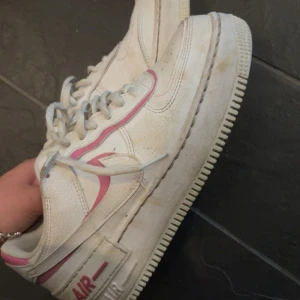 Nike Air Force 1 vita och rosa sneakers - Nike air force shadow med rosa detaljer. Jag har inte använt dom mycket, finns såklart lite smuts här och där med lätt att tvätta bort. Strl 38,5☺️