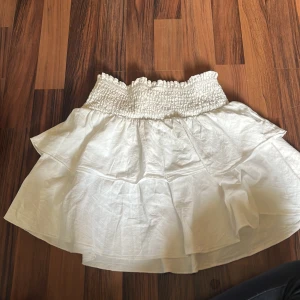 Vit volangkjol från SHEIN XS - Supersöt vit kortkjol från SHEIN i storlek XS Petite. Kjolen har smockad midja och dubbla volanger som ger en flowy och luftig känsla. Perfekt för varma dagar och enkel att matcha med crop tops eller linnen.