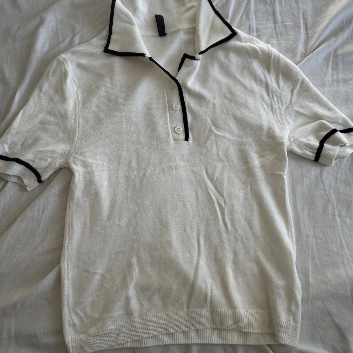 Vit pikétröja med svarta detaljer