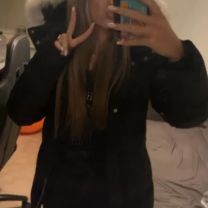 Svart pufferjacka Moose Knuckles M - Säljer en svart pufferjacka från Moose Knuckles med stor fluffig vit fuskpäls på huvan. Jackan har dragkedja, tryckknappar och flera fickor. Perfekt för kalla dagar och riktigt snygg siluett. Klassisk logga på insidan och detaljer i silver.