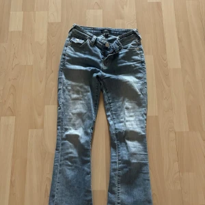 True Religion bootcut jeans ljusblå - Ljusblå jeans från True Religion i modellen Becca Mid Rise Bootcut. Klassisk femficksdesign, snygga detaljer på bakfickorna och en bootcut passform. Jeansen är i mjukt denimtyg och har en medelhög midja. Perfekta för dig som gillar en avslappnad men ändå trendig look💕 har en liten fläck men som finns med på bilderna annars är dom i helt nytt skick 