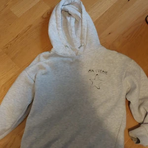 Grå hoodie från Gina Tricot med tryck - Grå hoodie från Gina Tricot med svart tryck 'MA CHÉRIE' och en stjärna på både fram- och baksidan. Stl.140 men passar 152
