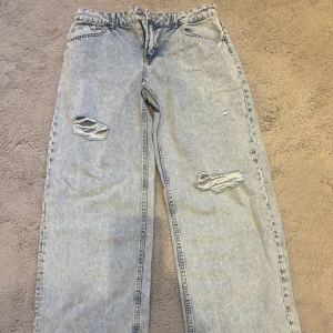 Ljusblå vida jeans  - Ljusblå jeans med slitna detaljer och vida/baggy ben. Klassisk femficksmodell med medelhög midja och dragkedja. Snyggt stentvättad denim som ger en cool vintagekänsla. Perfekta för en avslappnad streetstil.