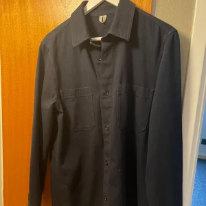 Blå overshirt  - Säljer denna snygga overshirt med knappar från arket! Passar dig som är 180-190. Bara höra av sig vid funderingar! Pris kan självklart diskuteras:)