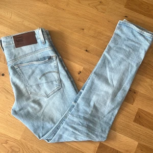 Ljusblå jeans från G-Star RAW - Säljer ett par ljusblå jeans från G-Star RAW i klassisk femficksmodell. Jeansen är slim fit passform. Snygga detaljer med läderpatch bak och broderad logga vid bakfickan. Perfekta till en avslappnad stil. 