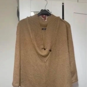 Beige stickad tröja från Gina Tricot - Mysig beige stickad tröja från Gina Tricot i storlek L. Tröjan har en bred ribbad krage med två knappar och långärmad passform. Perfekt för lager-på-lager och chill höst- och vinterstil. Storleken är L men passar M-XL också 