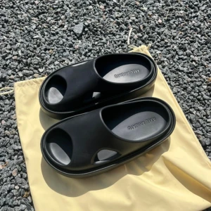 Svarta sandaler Axel Arigato Magma - Chunky svarta sandaler från Axel Arigato med modern, minimalistisk design. Tillverkade i syntetmaterial med öppen tå och coola utskurna detaljer på sidorna. Perfekta för sommardagar när du vill ha en clean och trendig look.