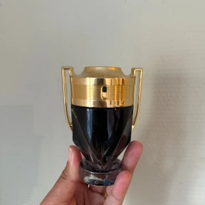Parfym Rabanne  - Parfym med unik troféformad flaska och guldiga detaljer. Märkt  med 'Invictus' på locket. Perfekt för dig som vill sticka ut med en snygg accessoar på hyllan. Oerhört stilig doft.  Mängd Rött streck sista bilden .