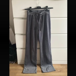 Gråa mjukisbyxor med snörning - Mysiga grå mjukisbyxor i mjukt material med breda ben och snörning i midjan. Perfekta för chill dagar hemma eller när du vill vara bekväm men ändå se snygg ut. Snygg loose fit och enkel design som passar till allt.