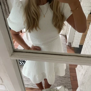 Studentklänning - Säljer nu min supersöta studentklänning som har  puffiga korta ärmar med en volangkant nedtill. Den har en öppen rygg med en fin rosett som knyts i nacken. Klänningen är figursydd upptill vilket gör den otroligt smickrande och tidlös🥹Den är även tjock och lyxig i tyget enligt mig! ✨