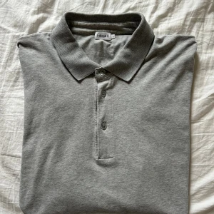 Grå långärmad pikétröja Filippa K - Grå långärmad pikétröja från Filippa K. En klassiskt designad tröja i grå bomull. Enkelt och stilrent. 