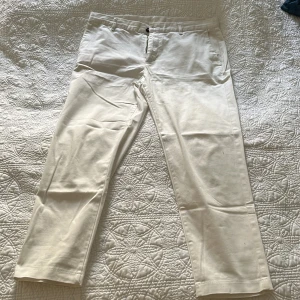 Vita kostymbyxor från Zara - Snygga vita kostymbyxor från Zara med raka ben och klassisk passform. Byxorna har hällor för bälte, sidfickor och bakfickor med knapp. Perfekta för en clean och stilren look. Materialet är mjukt och känns lyxigt.