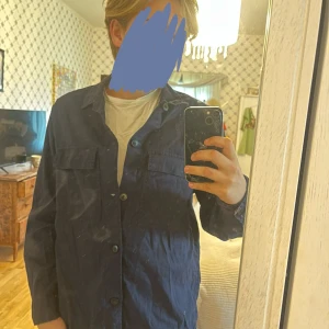 Mörkblå overshirt från H&M - Säljer en mörkblå overshirt från H&M i regular fit. Jackan har klassisk krage, knäppning framtill och två bröstfickor med lock. Perfekt att slänga över en t-shirt för en chill look. Passar M-L