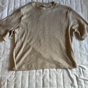 Beige ribbad topp från 157 XS - Säljer en beige ribbad topp från 157 i storlek XS. Toppen har korta ärmar, rund halsringning och är tillverkad i ett mjukt, stickat material. Perfekt för dig som gillar en enkel och stilren look med lite struktur.