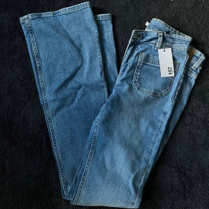  Blå jeans bootcut - Snygga blå Levi's 517 jeans med klassisk bootcut-passform. Jeansen har fem fickor, hällor för bälte och en ljusblå tvätt. Perfekta för dig som gillar en tidlös och avslappnad stil. Märkeslapp och etikett kvar på byxan.