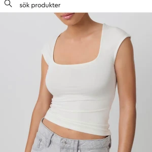 Vit croppad topp från Gina Tricot - Säljer en stilren vit croppad topp från Gina Tricot. Toppen har en fyrkantig ringning, ärmlös design med breda axelband och sitter figurnära. Perfekt att matcha med jeans eller kjol för en fräsch look.