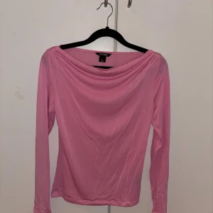Rosa långärmad topp från Monki XS - Säljer en rosa långärmad topp från Monki i storlek XS. Toppen har en snygg draperad halsringning och är figurnära i modellen. Perfekt att styla med jeans eller kjol för en trendig look.
