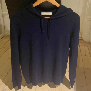 Kashmir hoodie  - Mysig mörkblå hoodie från Sayless i lyxig kashmir. Tröjan har huva med snörning och långa ärmar, perfekt för dig som gillar en stilren och enkel look. Supermjuk och skön att bära, passar dig som vill ha något både snyggt och bekvämt.