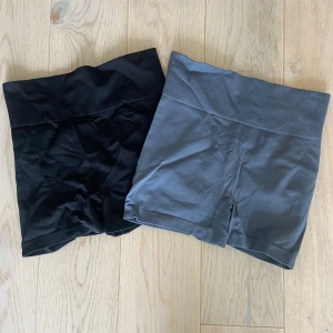 Svarta och grå seamless shorts S - Två par seamless shorts i storlek S, ett par svarta och ett par grå. Båda har bred, ribbad hög midja och är tillverkade i stretchigt material med 92% polyamid och 8% elastan. Perfekta för träning eller chill, med tight passform och scrunch-detalj bak.