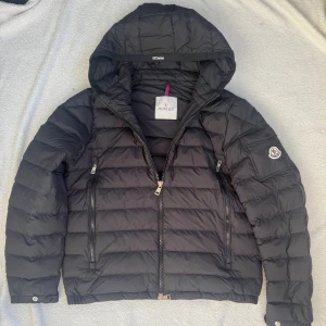 Moncler jacka  - Säljer en helt ny  svart pufferjacka från Moncler med huva - storlek 2 - passar medium/small |modellen har medium vanligtvis | passar skitbra inför hösten samt vintern då jackan värmer bra. Om du undrar varför så lågt pris så skulle jag tänka lite logiskt