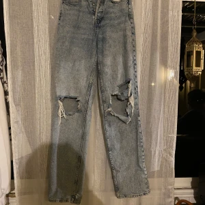 Blå ripped jeans från Divided - Snygga blå jeans från Divided med raka ben och stora slitningar över knäna. Jeansen har en klassisk femficksmodell och är tillverkade i bomull. Perfekta för en avslappnad och trendig look.