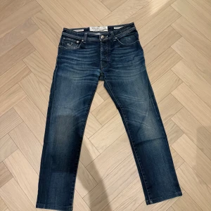Jacob Cohen mörkblå jeans 688 Comfort - Snygga mörkblå jeans från Jacob Cohen, modell 688 Comfort. Klassisk femficksdesign med silverfärgade knappar och detaljer. Jeansen har raka ben och en diskret tvättad look. Materialet är mjukt jeans med inslag av stretch för extra komfort.