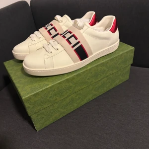 Gucci sneakers med röd metallic-detalj - Säljer ett par riktigt feta Gucci skor i storlek 44. Dem är aldrig använda. Kan gå ner i pris vid snabb affär!