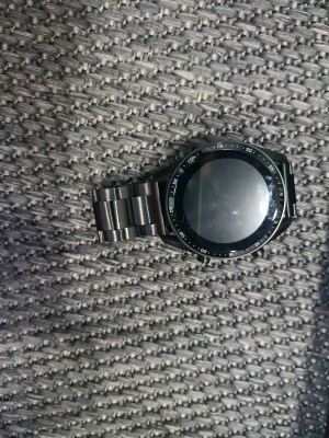 Svart C300 Smartwatch med metallarmband - Säljer en svart C300 Smartwatch med rund stor skärm och metallarmband. Klockan har två knappar på sidan och kommer med laddare och originalförpackning. Perfekt för dig som vill ha koll på tiden och dina aktiviteter direkt på handleden. Klockan kan också bli mindre eller större.