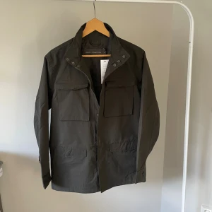Fieldjacka French connection -  Säljer en helt nyfield jacka från märket french connection med prislapp kvar. Jackan är mörkbrun/ khaki. Storlek small men passar även medium. Funkar både till hösten och vintern!