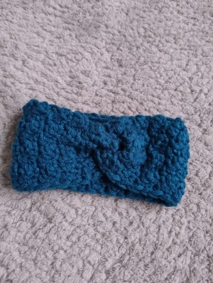 Turkost virkat pannband med twist - Snyggt turkost virkat pannband med twistad detalj framtill som jag gjort själv. Perfekt för att hålla öronen varma och samtidigt ge en cool touch till din look. Mjukt och tjockt material som sitter skönt runt huvudet.