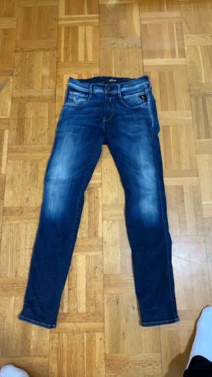 Replay Anbass blå jeans herr - Snygga Replay Anbass jeans i mörkblå tvätt med coola slitningar och klassiska fem fickor. Slim passform och raka ben ger en modern look. Jeansen har detaljerade sömmar och är tillverkade i stretchigt bomullsmaterial för extra komfort. Priset kan diskuteras, har haffat på mig de kenske 8 gånger 