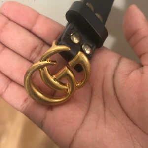 Svart bälte med guld spänne - Bältet är tillverkat i skinn och har en stilren, klassisk form med flera hål för justering. Aldrig använt. 