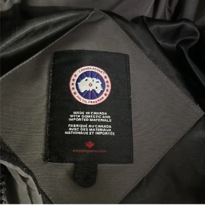 Canada Goose jacka - Säljer en svart dunjacka från Canada Goose Perfekt för kalla dagar och håller dig varm hela vinter. Problemet är att dragkedjan har gått sönder går och fixa. En liten fläck bakom luvan man ser knappt. Sen en knapp som har gått av. Dragkedjan fnnar inte