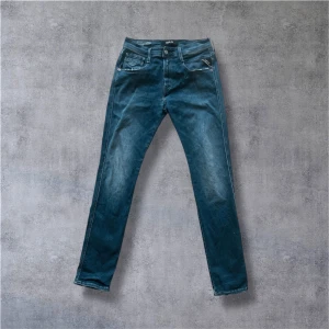 Replay Hyperflex  - Snygga Replay Hyperflex jeans i blå tvätt med klassisk femficksdesign och raka ben. Jeansen har en normal passform och är tillverkade i stretchigt jeansmaterial för extra komfort. Perfekt för dig som gillar stilrena och bekväma jeans. Bra skick och håller på att få fade!