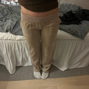 Beige mjukisbyxor Juicy Couture S - Säljer ett par beige mjukisbyxor från Juicy Couture i storlek S. Byxorna har bred resårmidja med snörning, stora fickor fram och bakfickor med knappdetaljer. Materialet är mjukt och har en lyxig känsla, perfekt för chill dagar. Skriv om ni har frågor😊